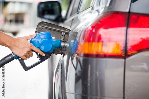 Hand refilling the car with fuel at the refuel station.