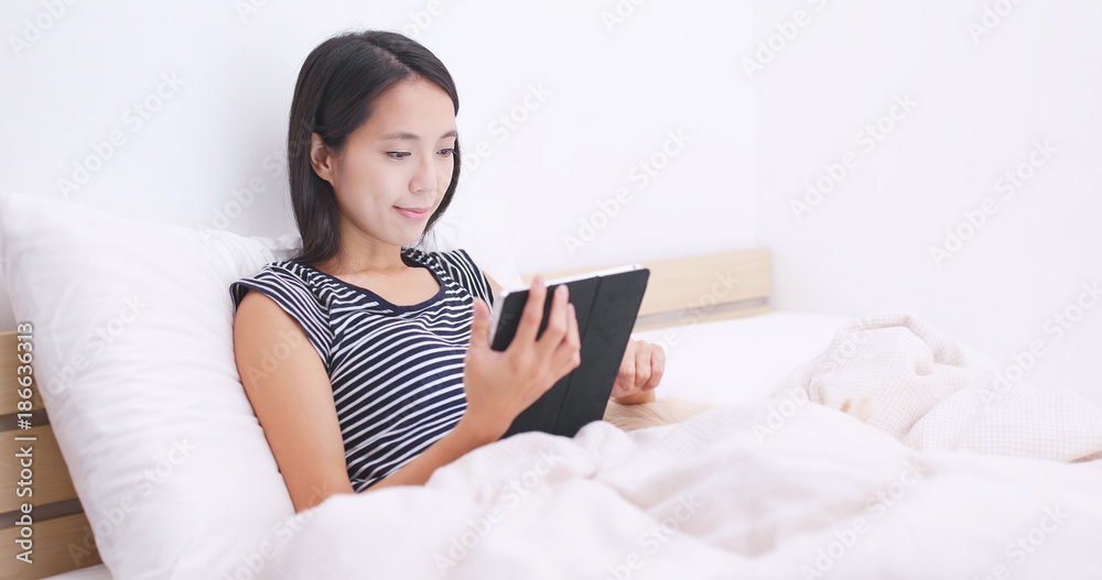 Woman watching on digital tablet and lying on bed with her dog Woman watching on digital tablet and lying on bed with her dog