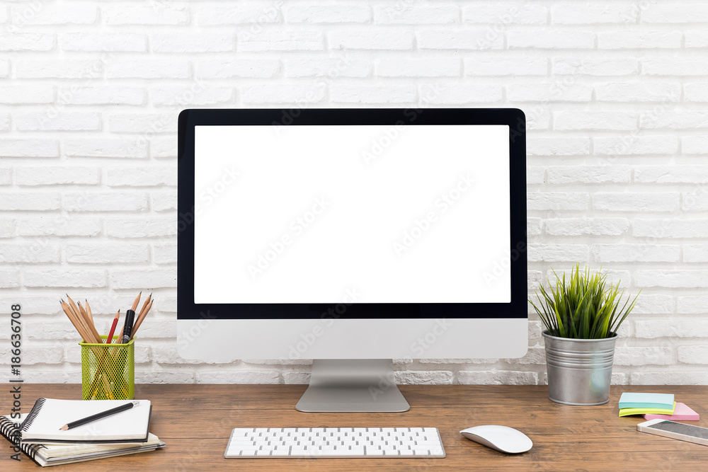 workspace with computer with blank white screen, and office supplies on a wooden desk workspace with computer with blank white screen, and office supplies on a wooden desk