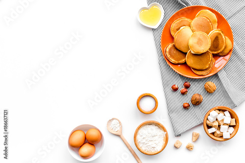 Cooking american pancakes. Ingredients, cakes, nuts and honey on white background top view copyspace photo