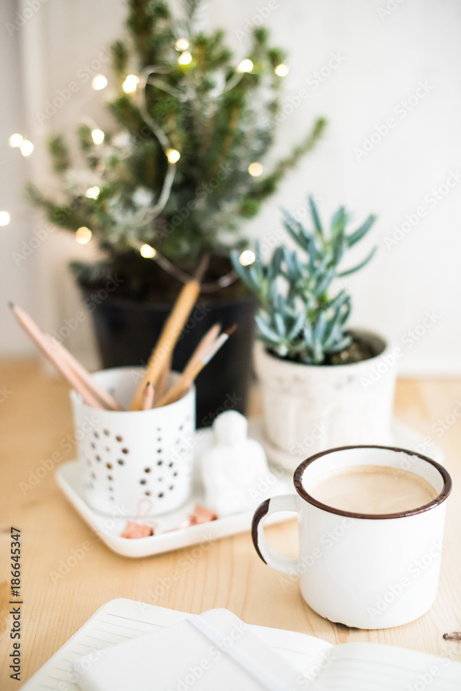 Mug of hot winter drink on table with home office details 