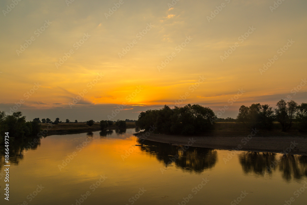 Colorful sunset over wild river in remote rural area, in autumn