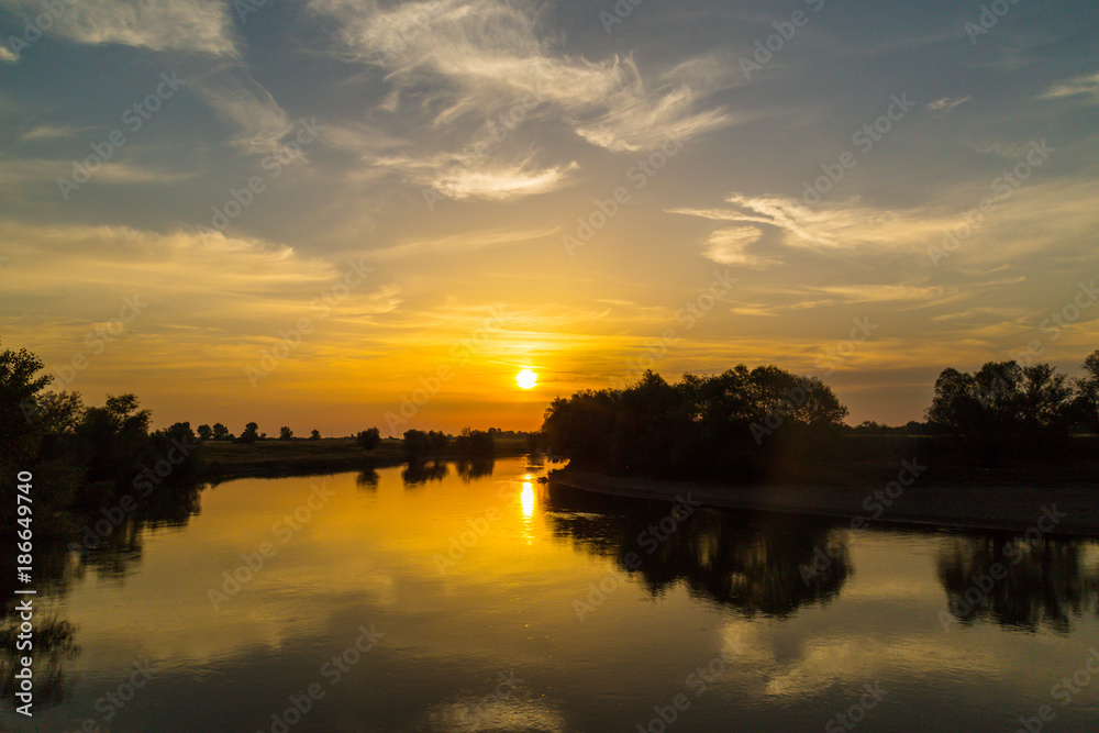 Obraz premium Colorful sunset over wild river in remote rural area, in autumn