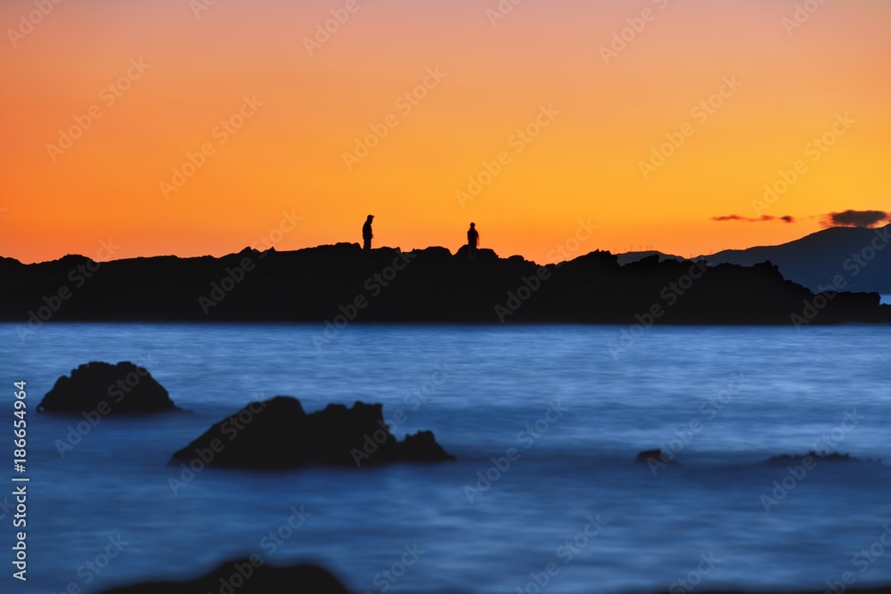 Humans silhouette on the reef at suset slow shutter 