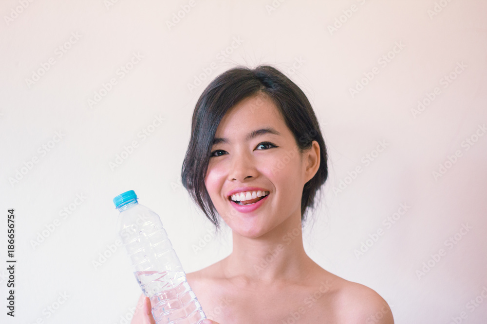 Beauty Skincare concept- Young Asian woman after shower smiling holding a bottle of water Beauty Skincare concept- Young Asian woman after shower smiling holding a bottle of water