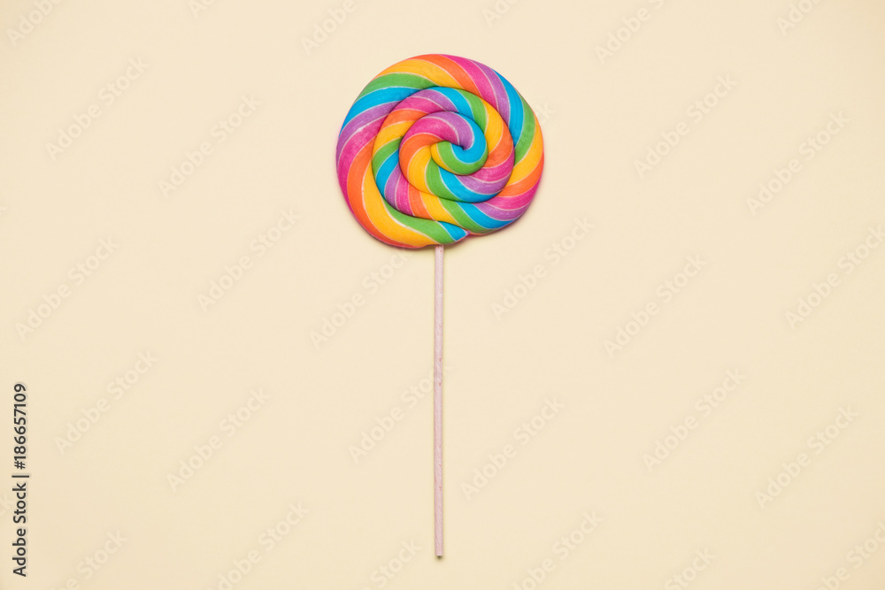 Lollipop swirl on wooden stick on beige paper background Lollipop swirl on wooden stick on beige paper background