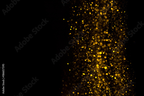 Falling glitter dust bright bokeh border on black background with copy space