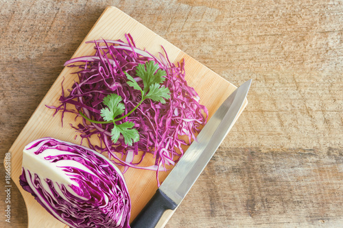 Sliced fresh purple or red cabbage on wood cutting board decorate with coriander in top view flat lay with copy space. Prepare vegetable for cooking cabbage salad or coleslaw. Homemade food concept.