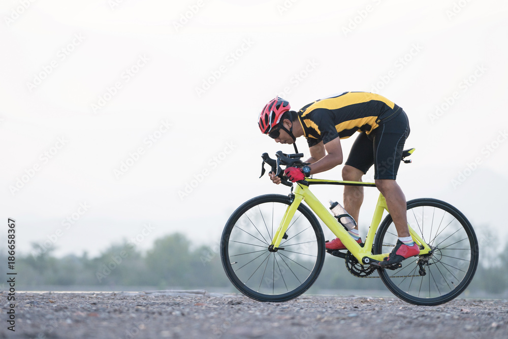 Road bike cyclist man cycling. Biking sports fitness athlete riding bike on an open road to the sunset.