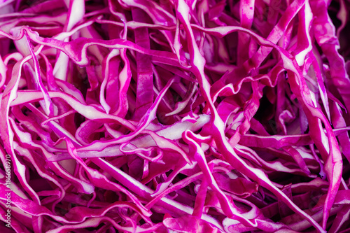 Close up sliced or shredded fresh purple or red cabbage in top view flat lay to present surface and texture of cabbage can apply for background or wallpaper. Vegetable pattern concept in macro style.