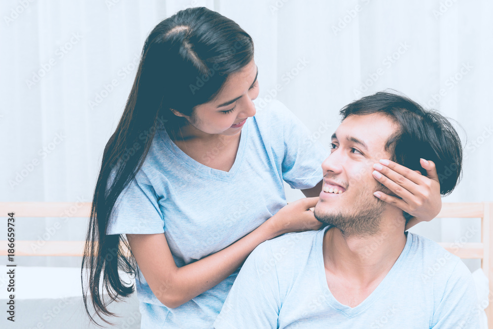 Mixed race lovers concept. Young white male in his bedroom getting intimate with his pretty young chinese girlfriend. Wearing blue jeans, blue shirt and in their early twenties. Taken indoor. Mixed race lovers concept. Young white male in his bedroom getting intimate with his pretty young chinese girlfriend. Wearing blue jeans, blue shirt and in their early twenties. Taken indoor.