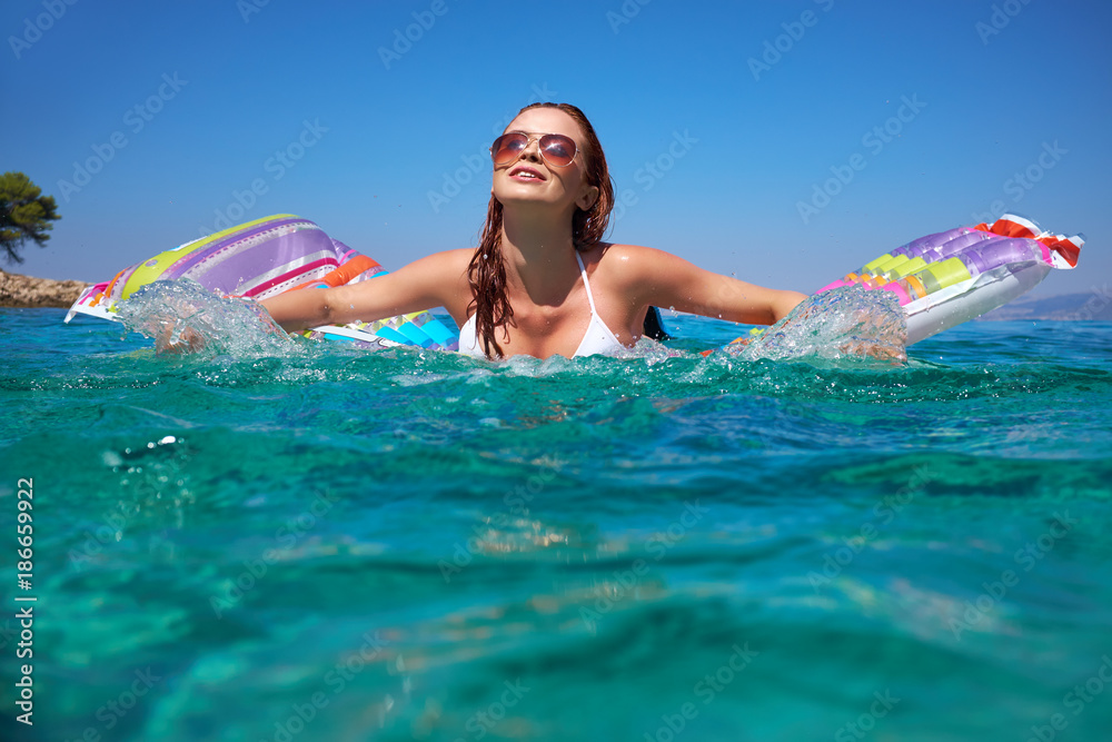 summer holidays, vacation, travel and people concept - smiling young woman in sun hat on beach over sea and blue sky background