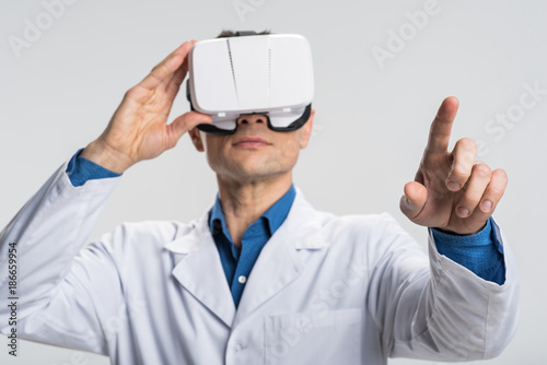 Virtual database. Experienced pleasant male doctor emerging in VR while standing on the isolated background and gesturing 