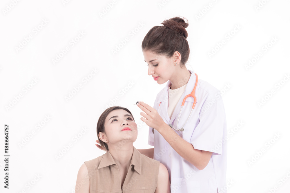 Professional medical career concept. Young female doctor with stethoscope, white cloth isolated in white. Using eye drop into her female chinese patient with eye pain. Professional medical career concept. Young female doctor with stethoscope, white cloth isolated in white. Using eye drop into her female chinese patient with eye pain.