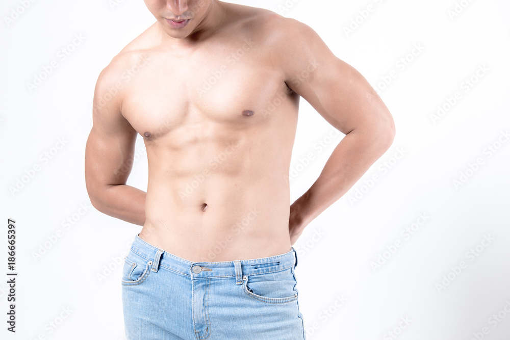 Fitness and health concept. Fit sport man flexing his body showing his six packs, isolated on white background. Half naked Asian chinese lean muscular male wearing jeans.