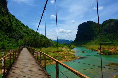 Hanging bridge with a view of green water stream in Phong Nha, Ke Bang National Park, Vietnam photo
