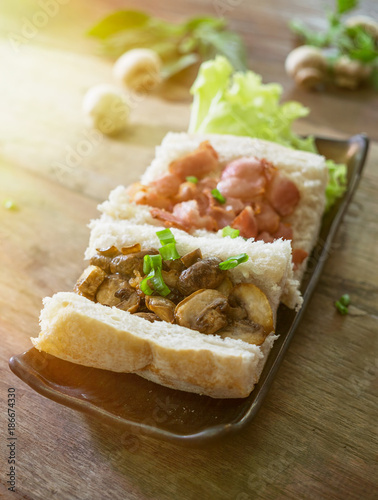 open mushroom bacon sandwich with spring onion in plate on wooden table. Rustic food background. Warm filtred