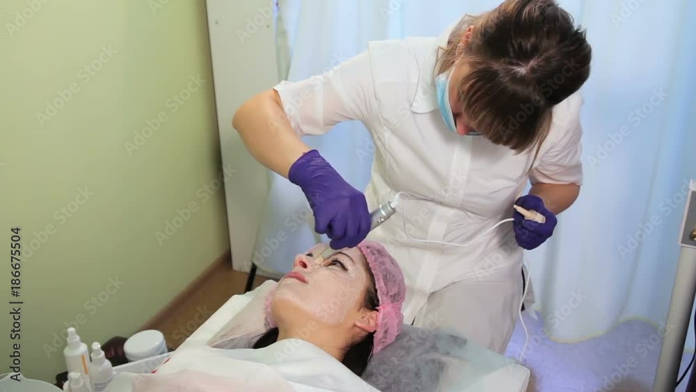 The procedure of lightening the skin. The esthetician in a medical gown and gloves performs manipulation. The procedure of lightening the skin. The esthetician in a medical gown and gloves performs manipulation.