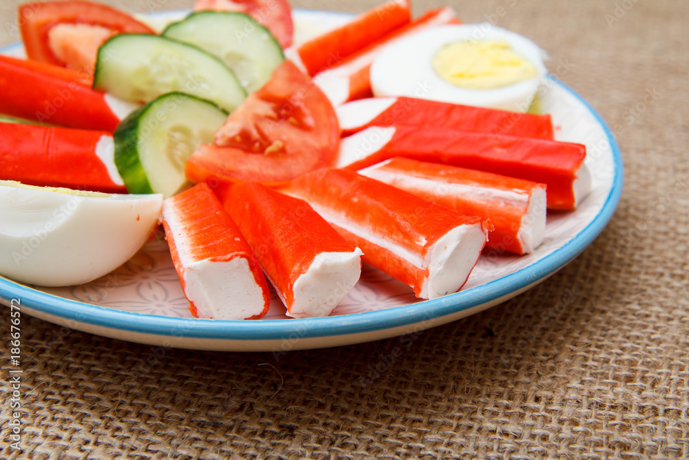 Plate with crab sticks, boiled egg and freshly sliced tomato and cucumber Plate with crab sticks, boiled egg and freshly sliced tomato and cucumber