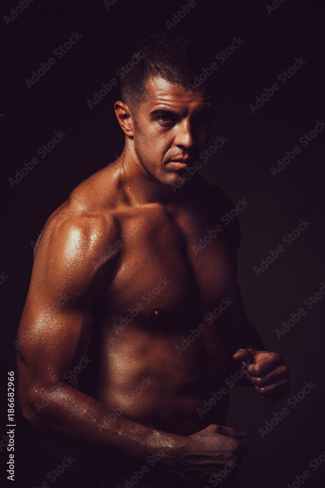 Fototapeta premium Athletic young bodybuilder shows muscles after a workout. Concept handsome sport man.