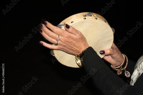 Photo beautiful female hands banging the tambourine,black background