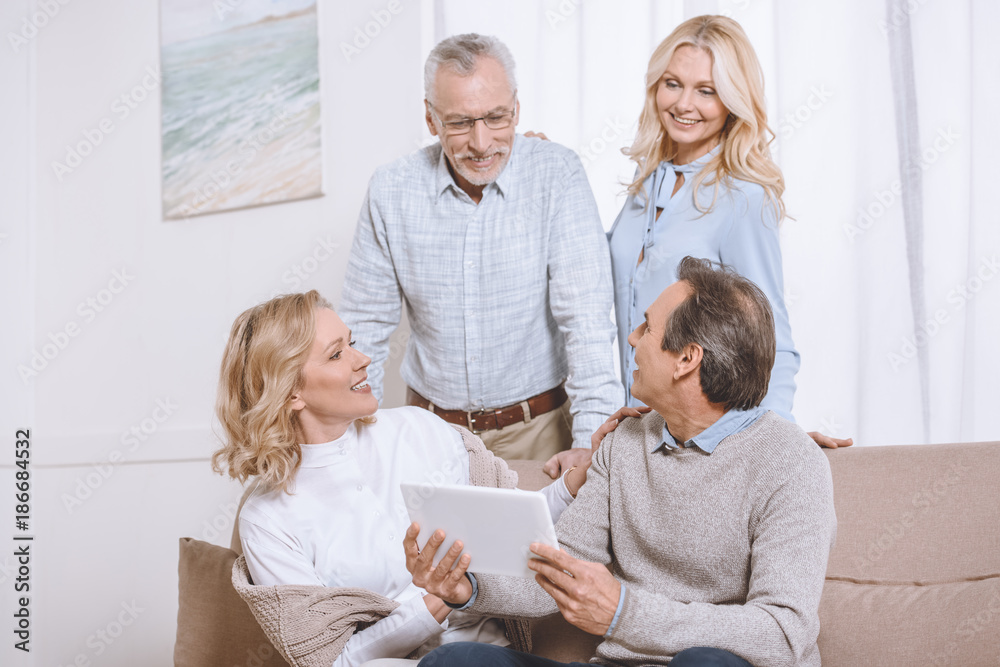 Fototapeta premium Senior men and women using digital tablet while sitting on sofa