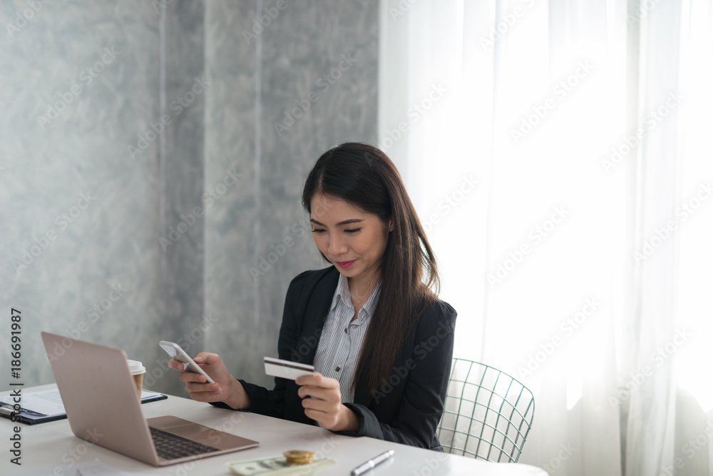 Beautiful asian young businesswoman holding phone and credit card  buying on line. Online shopping, technology concept.
