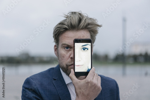 Businessman holding cell phone with image of a woman in front of his eyes