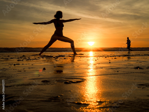 Frau macht Yoga am Strand bei Sonnenuntergang