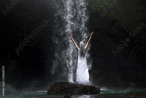 Beautiful senior woman standing in front of a tropical waterfall