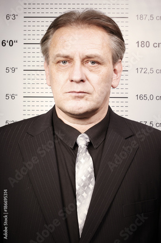 Criminal man portraited in front of mug board