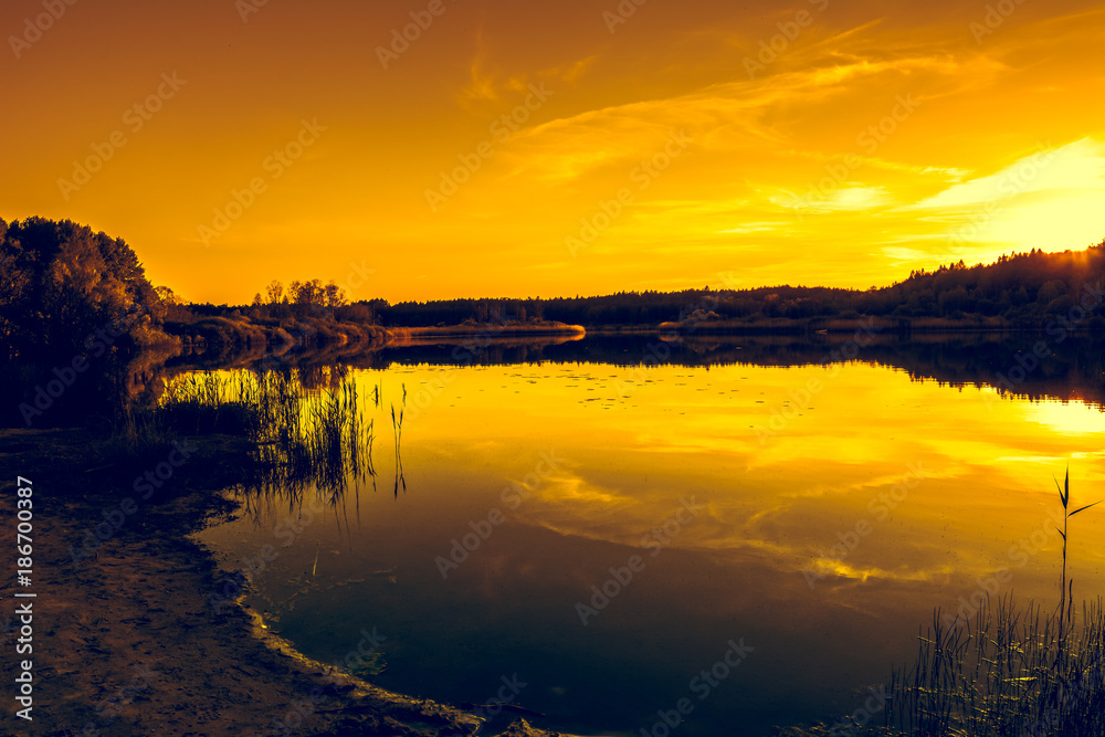 Summer scenery of sunset sky over peaceful lake with calm water surface, nature landscape