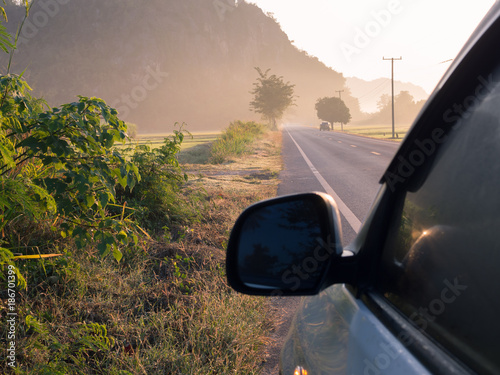 The car on the road in front of the mountain.