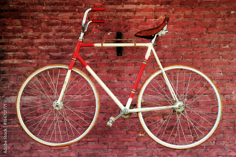 Old bicycle on a background of red brick wall. Bangkok, Thailand.