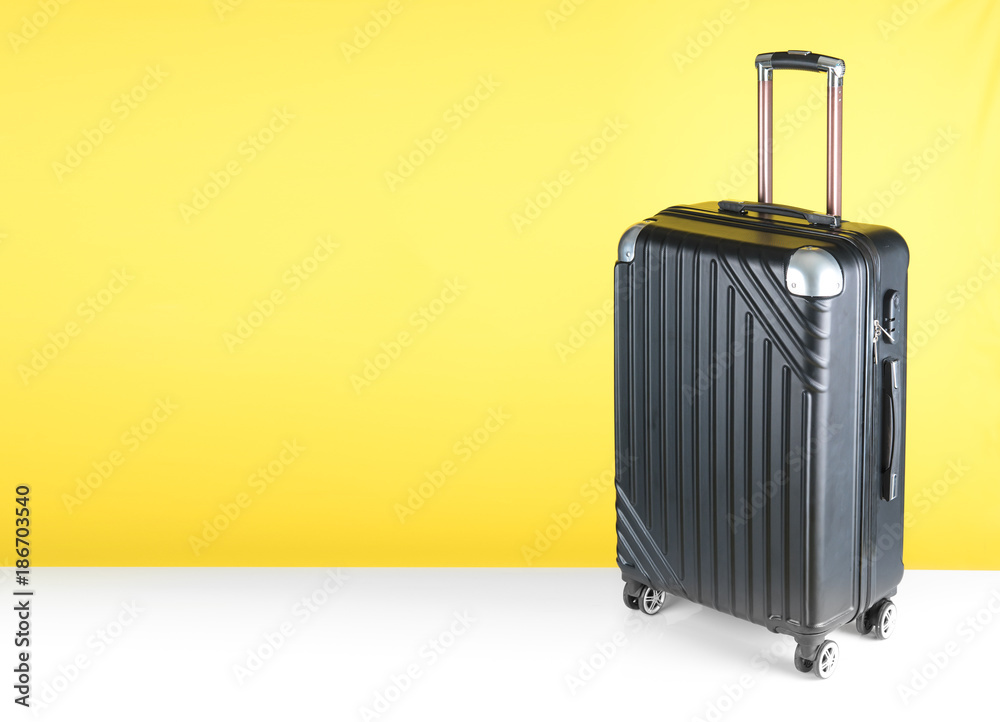 Plastic suitcase against yellow background Plastic suitcase against yellow background