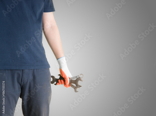 Handyman holding wrenchs on gray background