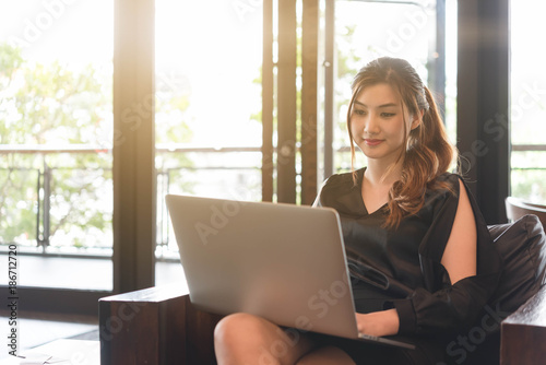 Beautiful asian woman in black dress working with laptop in coffeeshop