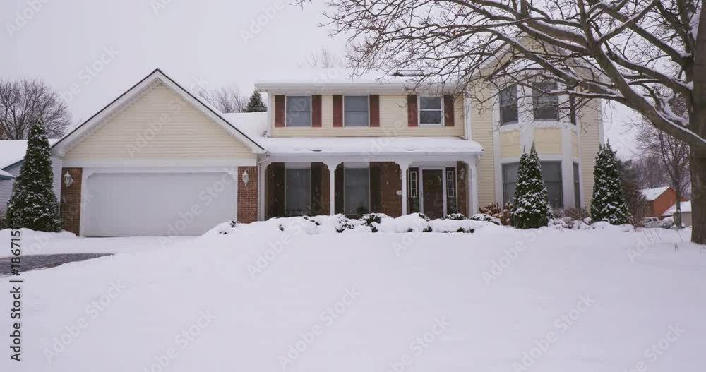 Yellow Colonial Home in Winter Tilt Up. view tilts up on a the exterior of a yellow suburban home during a snowy day Yellow Colonial Home in Winter Tilt Up. view tilts up on a the exterior of a yellow suburban home during a snowy day