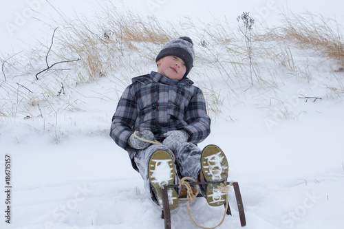 a funny boy sitting on sledges