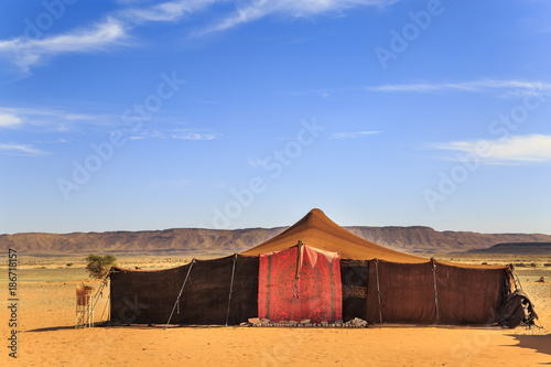 A tent made of camel skin in desert with mountains on background photo