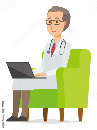 A middle-aged male doctor wearing a white suit sitting on a sofa and operating a laptop computer