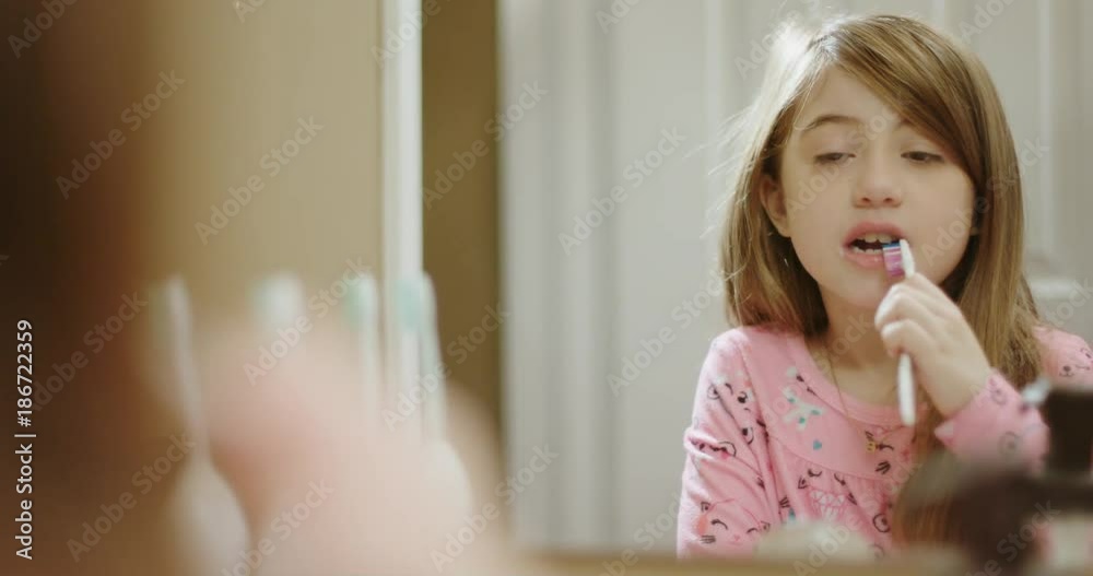 Young Girl Brushes Her Teeth in Mirror. view moves right and reveals a little girl brushing her teeth looking into a mirror Young Girl Brushes Her Teeth in Mirror. view moves right and reveals a little girl brushing her teeth looking into a mirror