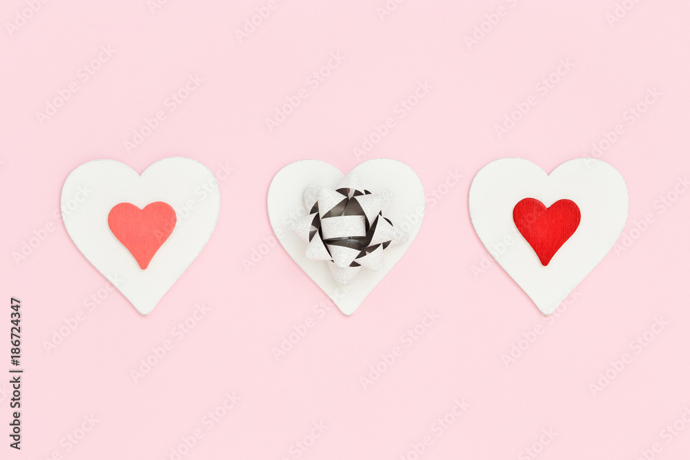 Three hearts on pink. Valentine's Day greeting card. Holiday background with heart & pull bow. Flat lay. I love You concept