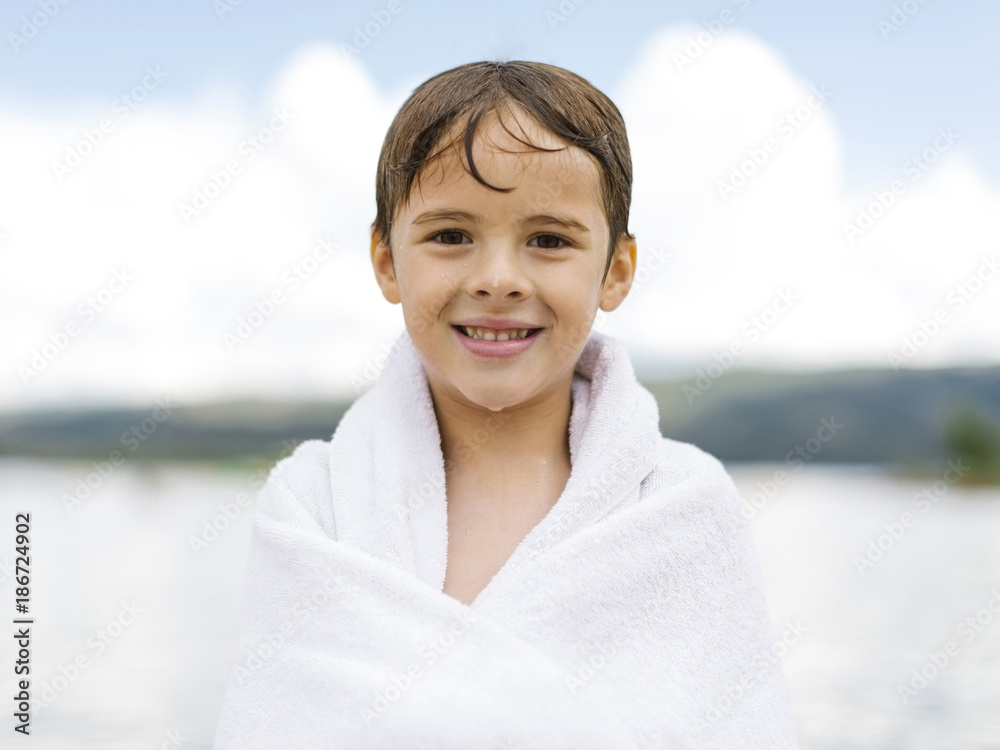Portrait of boy (6-7) wrapped in towel by lake