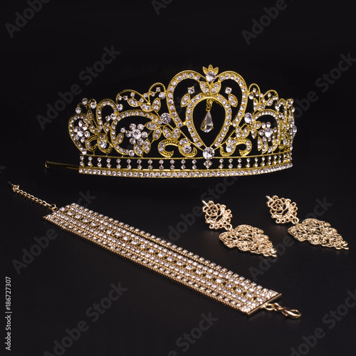 set of crown, earrings, bracelet isolated on black