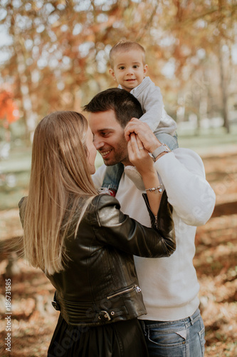Happy young parents with baby boy in autumn park