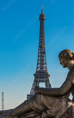 Eiffel Tower behind the statue of a seated woman © XtravaganT