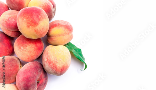 Heap of fresh ripe peaches with leaves on white background.