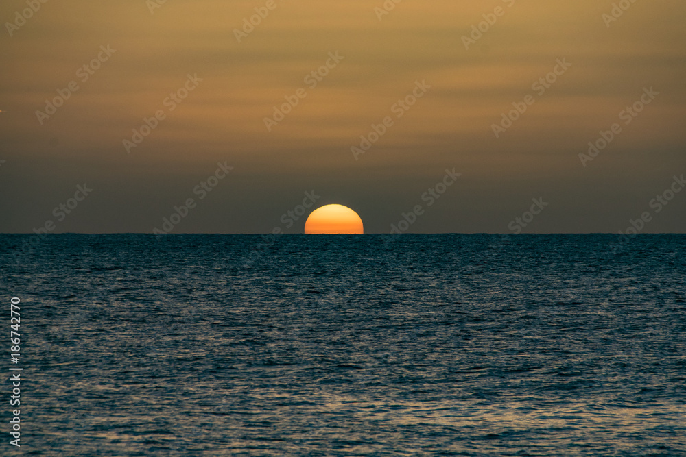 Golden sunset over a calm still ocean sea