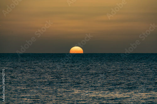 Fototapeta Naklejka Na Ścianę i Meble -  Golden sunset over a calm still ocean sea
